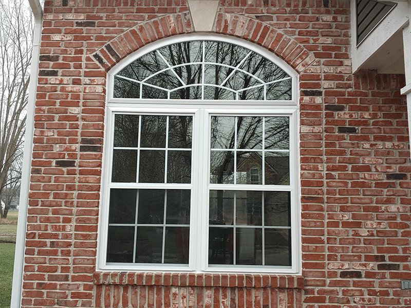 Twin double hung windows with grids and an arched transom.